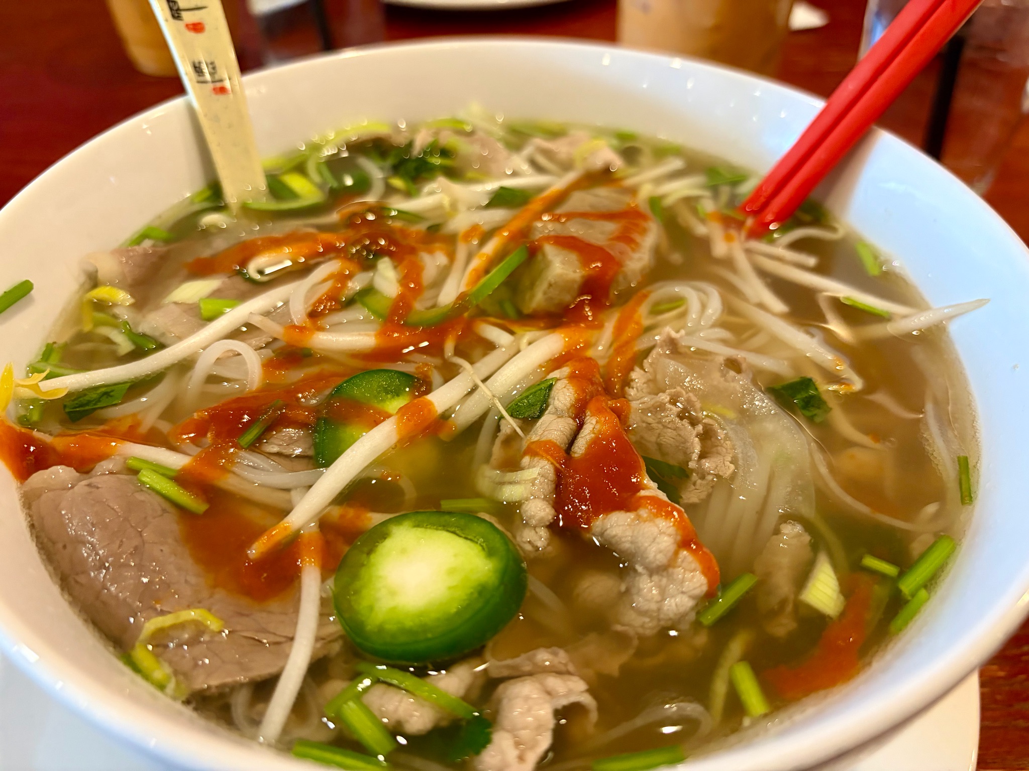 A bowl of pho with brisket, eye round, and meatballs